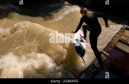 Monaco, Germania. 21 luglio 2021. Un uomo cavalca l'onda di Eisbach nel Giardino Inglese. L'onda artificiale è considerata un punto di riferimento popolare per surfisti e spettatori tutto l'anno. Credit: Peter Kneffel/dpa/Alamy Live News Foto Stock