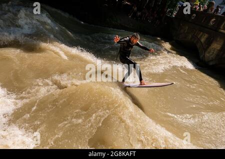 Monaco, Germania. 21 luglio 2021. Il muro Keegan, nato in Australia, cavalca l'onda di Eisbach nel Giardino Inglese. L'onda artificiale è considerata un punto di riferimento popolare per surfisti e spettatori tutto l'anno. Credit: Peter Kneffel/dpa/Alamy Live News Foto Stock