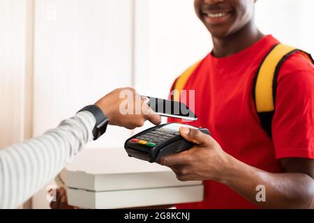 Lady Putting Phone al terminale Corriere a pagamento per Pizza Indoor Foto Stock