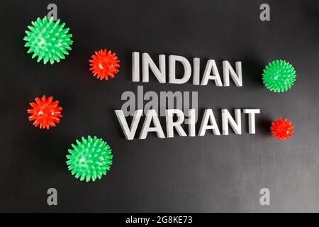 parole variante indiana posata con lettere in metallo d'argento superficie opaca nera con piccoli modelli di virus rosso e verde in prospettiva inclinata Foto Stock