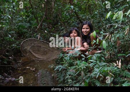 Tre ragazze si sono levate in piedi con una rete di pesca vicino al fiume. AMAZZONIA ECUADOR: In un'immagine, una donna indossava il trucco rosso attraverso i suoi occhi e un tegole sfumato Foto Stock