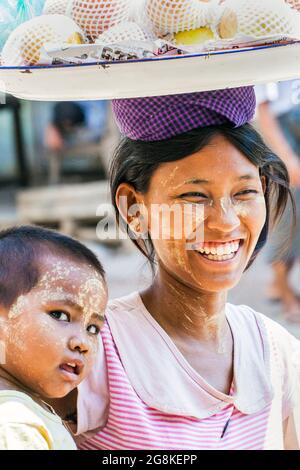 Giovane bella donna birmano venditrice di frutta a lato della strada che vende mele da vassoio sulla testa, Monywa a Bagan, Myanmar Foto Stock