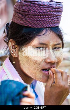 Primo piano di giovane piuttosto donna birmano vendor di frutta con Thanaka cosmetic pasta gialla su faccia, Monywa a Bagan, Myanmar Foto Stock