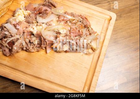 Colpo ad angolo alto di carne cotta tritata con cipolle su una tavola di legno Foto Stock