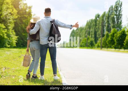 Uomo e donna che fermano l'auto su strada, vista posteriore Foto Stock