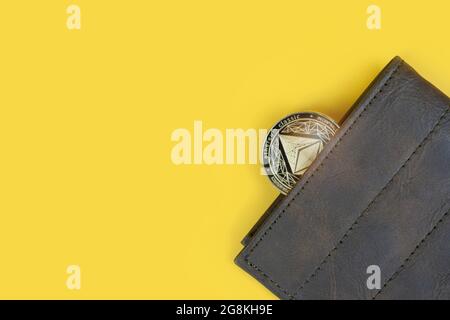 Moneta da cripto etereum o Eth in un portafoglio marrone in pelle su sfondo giallo con spazio per la copia. Banner con spazio per il testo. Foto Stock