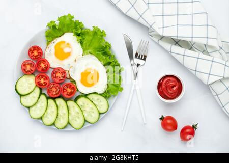 Uova di pollo fritte con verdure su un tavolo grigio. Concetto di colazione. Vista dall'alto. Composizione di posa piatta. Cibo di sottofondo al mattino. Cubetti freschi a fette Foto Stock