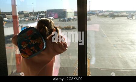 Bambina che guarda l'aereo parcheggiato all'aeroporto di Mosca attraverso la finestra del cancello. Manutenzione e preparazione dell'aeromobile per il reggimento Foto Stock