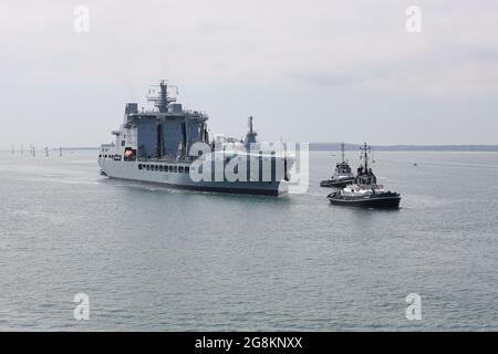 I Tugs guidano la petroliera ausiliaria di rifornimento della Royal Fleet TIDESURGE (A138) verso l'entrata del porto Foto Stock