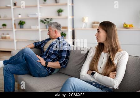 Sconvolgere la donna matura e il marito seduti a parte sul divano a casa dopo il litigio, sentendosi offesi, avendo un conflitto Foto Stock