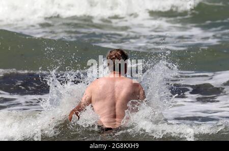 19 luglio 2021, Meclemburgo-Pomerania occidentale, Warnemünde: Un uomo cammina nel Mar Baltico, che è scagliato dal forte vento. Foto: Bernd Wüstneck/dpa-Zentralbild/ZB Foto Stock