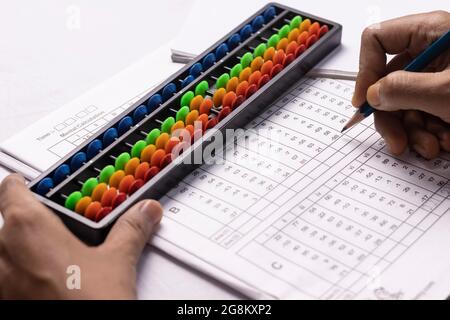 fuoco selettivo sulla mano umana che fa i calcoli di abacus su sfondo bianco Foto Stock