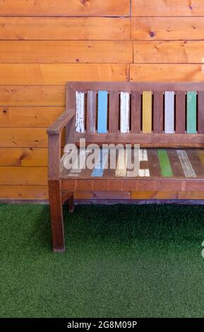 La panca in legno verniciato con il colore pastello sull'erba artificiale di fronte alla caffetteria, per il relax del cliente sulla terrazza, di fronte Foto Stock