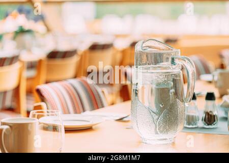 Interno accogliente del Summer Cafe. Caraffa di acqua ghiacciata Icy su tavolo e posate Foto Stock