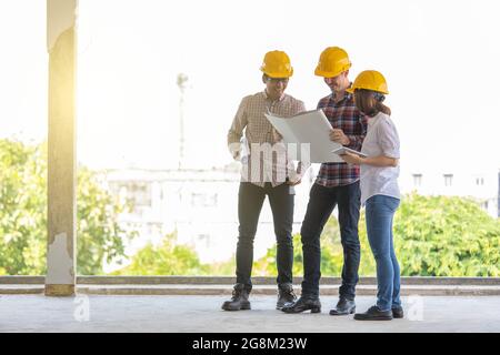 Diversi gruppi di ingegneri, asiatici e caucasici, uomini e donne che lavorano insieme in cantiere. Foto Stock