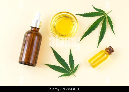 Gruppo di bottiglie di vetro e ciotola con olio cbd di cannabis, tintura di thc e foglie di canapa. Vista dall'alto, disposizione piatta Foto Stock