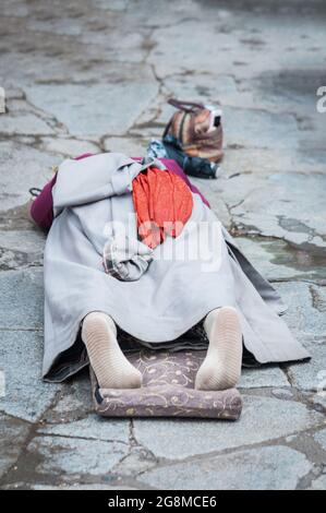 Pellegrina femminile giacente sul pavimento dopo essersi prostrata. Facendo il 'Barkhor Kora', un circuito devozionale di pellegrinaggio intorno al vecchio Tempio di Jokhang Foto Stock