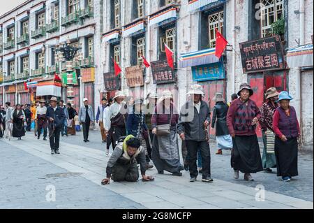 Pellegrini tibetani non identificati che eseguono il Barkhor Kora (camminando in senso orario intorno al Tempio di Jokhang) Foto Stock