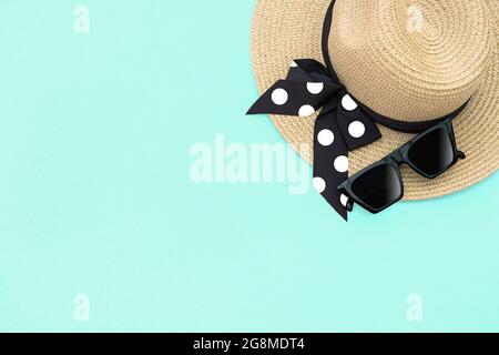 Moda estate piatto lay. Cappello di paglia e occhiali da sole su sfondo turchese Foto Stock