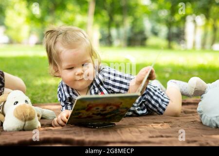 Dnepropetrovsk, Ucraina - 08.27.2017: Bambina con un libro aperto nelle mani. Il capretto guarda le immagini con interesse. Foto Stock