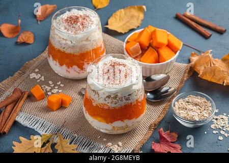 Due porzioni di dessert di zucca con crema e cacao su sfondo autunnale. Vista laterale, primo piano. Foto Stock