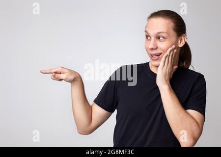 un giovane sorpreso in una t-shirt nera che punta il dito via Foto Stock
