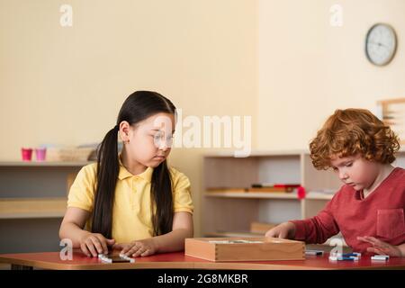 ragazza e ragazzo asiatici con capelli rossi giocando gioco educativo nella scuola di montessori Foto Stock