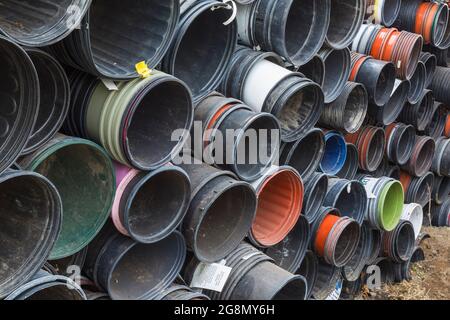 File di contenitori di plastica rotondi impilati per la coltivazione di piante all'interno di una serra Foto Stock