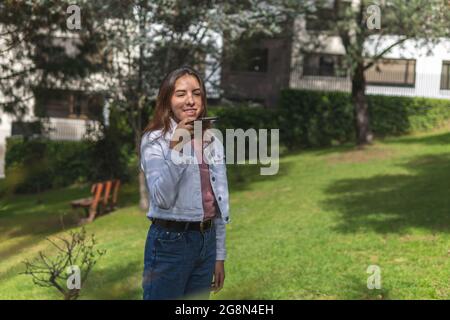 Latina teen girl inviando un messaggio audio all'aperto Foto Stock