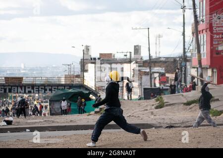 Un dimostratore lancia rocce e depred alla polizia in rivolta in Colombia durante una nuova giornata di proteste anti-governative durante la celebrazione del 211 dell'indipendenza della Colombia dalla spagna, proteste sollevate in scontri in varie città dopo l'intervento della polizia malata della Colombia ESMAD, a Bogotà, Colombia, il 20 luglio 2021. Foto Stock