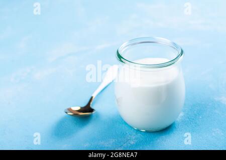 Yogurt greco in un vaso di vetro su sfondo blu. Spazio di copia Foto Stock