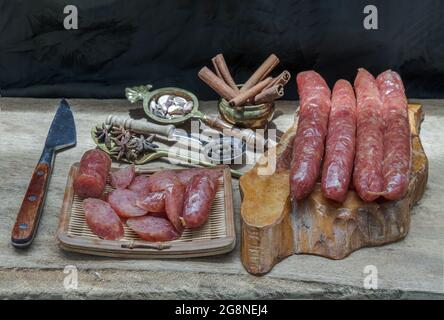 Salsiccia cinese secca con erbe su vecchio tavolo di legno. Stile alimentare asiatico, fuoco selettivo. Foto Stock