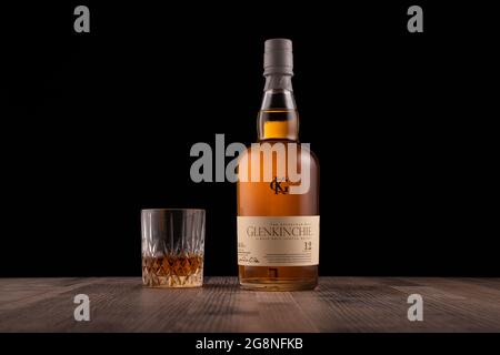 LISSE, PAESI BASSI - 17 LUGLIO 2021: Bottiglia Glenkinchie e bicchiere di whisky scotch di 12 anni su una superficie di legno su sfondo nero. (lan Foto Stock