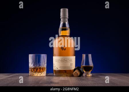 LISSE, PAESI BASSI - 16 LUGLIO 2021: Bottiglia Glenkinchie e bicchiere di whisky scotch di 12 anni su una superficie di legno su sfondo blu. Foto Stock