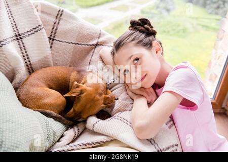 Ritratto di attraente calma ragazza preteen che riposa con carino doggy trascorrere il fine settimana in casa luce al chiuso Foto Stock