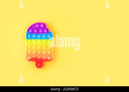 Spingere il giocattolo del fidget pop isolato su sfondo giallo. Foto Stock