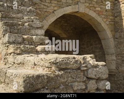 Arco in pietra in un edificio antico e mura in pietra in rovina Foto Stock