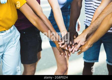 Primo piano gruppo multietnico di giovani studenti che si accatastano insieme le mani: Le persone millenarie che festeggiano insieme all'aperto Foto Stock