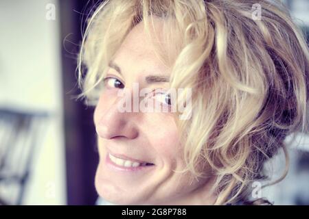 Primo piano ritratto di una giovane donna caucasica matura con capelli biondi al coperto. Foto Stock