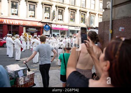 Glasgow, Scozia, Regno Unito. 21 luglio 2021. NELLA FOTO: Gli onlooker scattano foto sul proprio cellulare con fotocamera per registrare la band suonando una rappresentazione della Tune tema Indiana Jones. Girando sul set di Indiana Jones 5 nel centro di Glasgow, il campione d'incassi di Hollywood imposta Glasgow come New York City. Si può vedere una produzione completa, con un grande cast, produttori ed extra. Il centro della città è stato cambiato in modo che tutti i negozi e gli edifici assomiglia a 1959 America. Credito: Colin Fisher Foto Stock