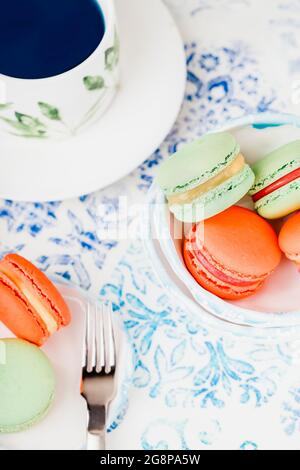 Tè blu farfalla e amaretti o macaron verdi e arancioni Foto Stock