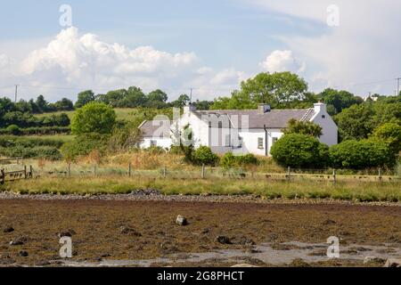 21 luglio 2021 UN piccolo bungalow bianco con il proprio molo di legno si trova sul bordo dell'acqua vicino a Gibbs Island su Strangford Lough nella contea in basso a nord i Foto Stock