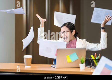 Donna d'affari asiatica arrabbiata gettando carte su se stessa in ufficio quando il lavoro fallisce, progetto fallito, lavoro duro e overworked e ha sottolineato Concep Foto Stock