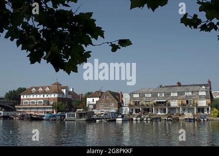 vista estiva sul fiume tamigi dai giardini di canbury verso le case e le barche ormeggiate di hampton wick, a sud-ovest di londra, inghilterra Foto Stock