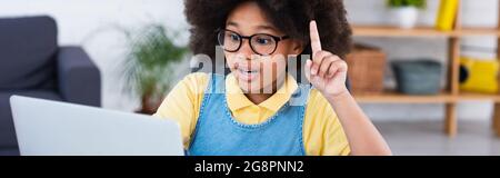 Ragazza afroamericana che ha idea durante l'istruzione in linea a casa, bandiera Foto Stock