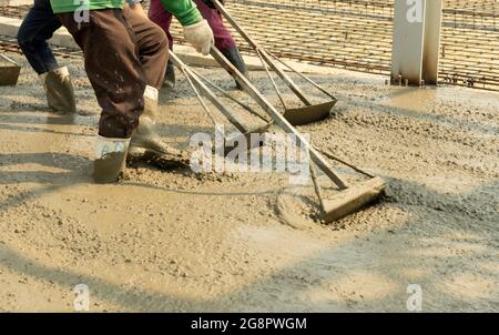 Tre lavoratori con acciaio liquido calcestruzzo regolmtnt. Foto Stock