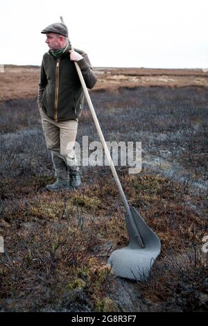 Tom Adamson, Gamekeeper per la Bolton Abbey Estate con un battitore che è usato per soffocare le fiamme durante la combustione di Moorland su Barden Moor nella Y Foto Stock