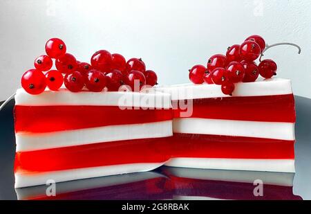 Due deliziosi pezzi di panna rossa e bianca. Torta decorata con viburnum Foto Stock