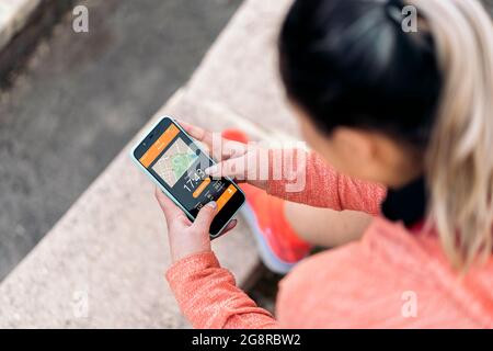 Donna attiva non riconosciuta con abiti sportivi utilizzando il suo telefono cellulare e controllare il suo allenamento. Foto Stock