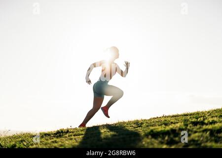 Donna attiva non riconosciuta con abiti sportivi che corrono nel parco e allenarsi. Foto Stock